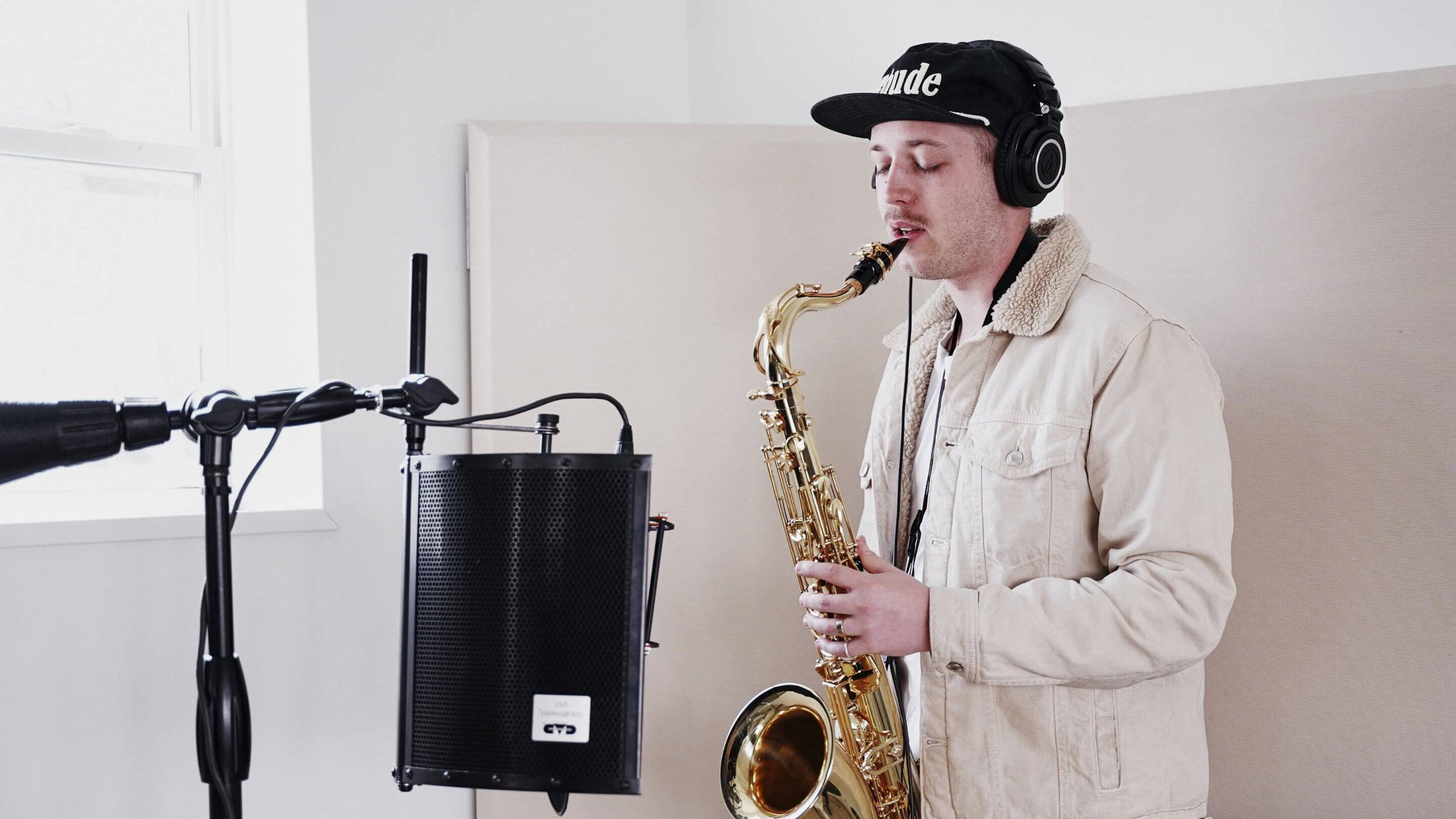 Musician playing saxophone in front of microphone.