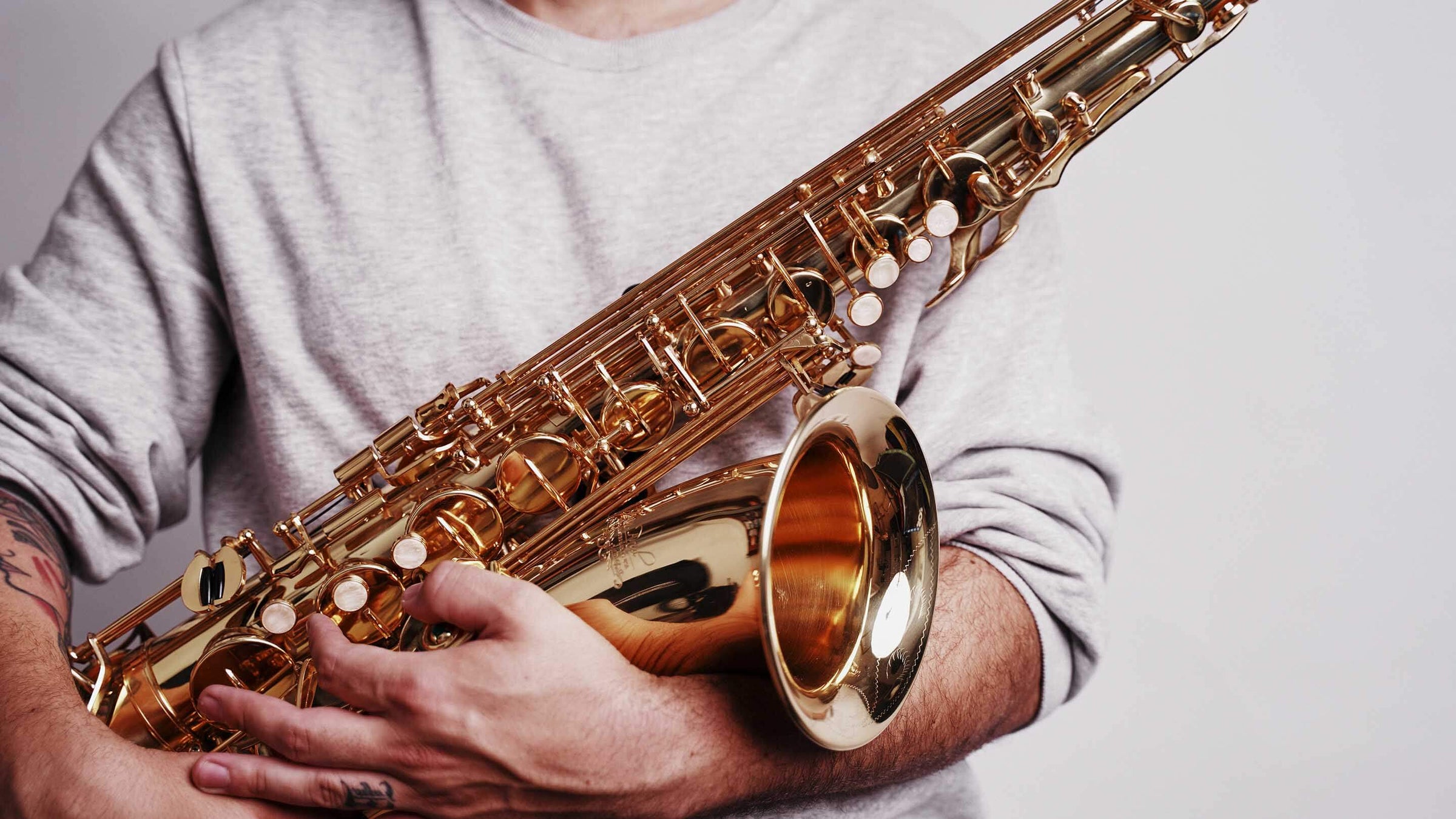 Musician holding saxophone in arms.